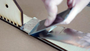 23 applying foil tape to laser cut plywood