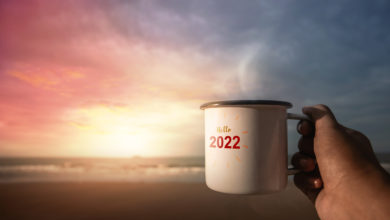 2022 Year Concept. Start a New Year by Drinking Hot Coffee on the Beach during Sunrise. Say Hello to 2022 Year. POV View