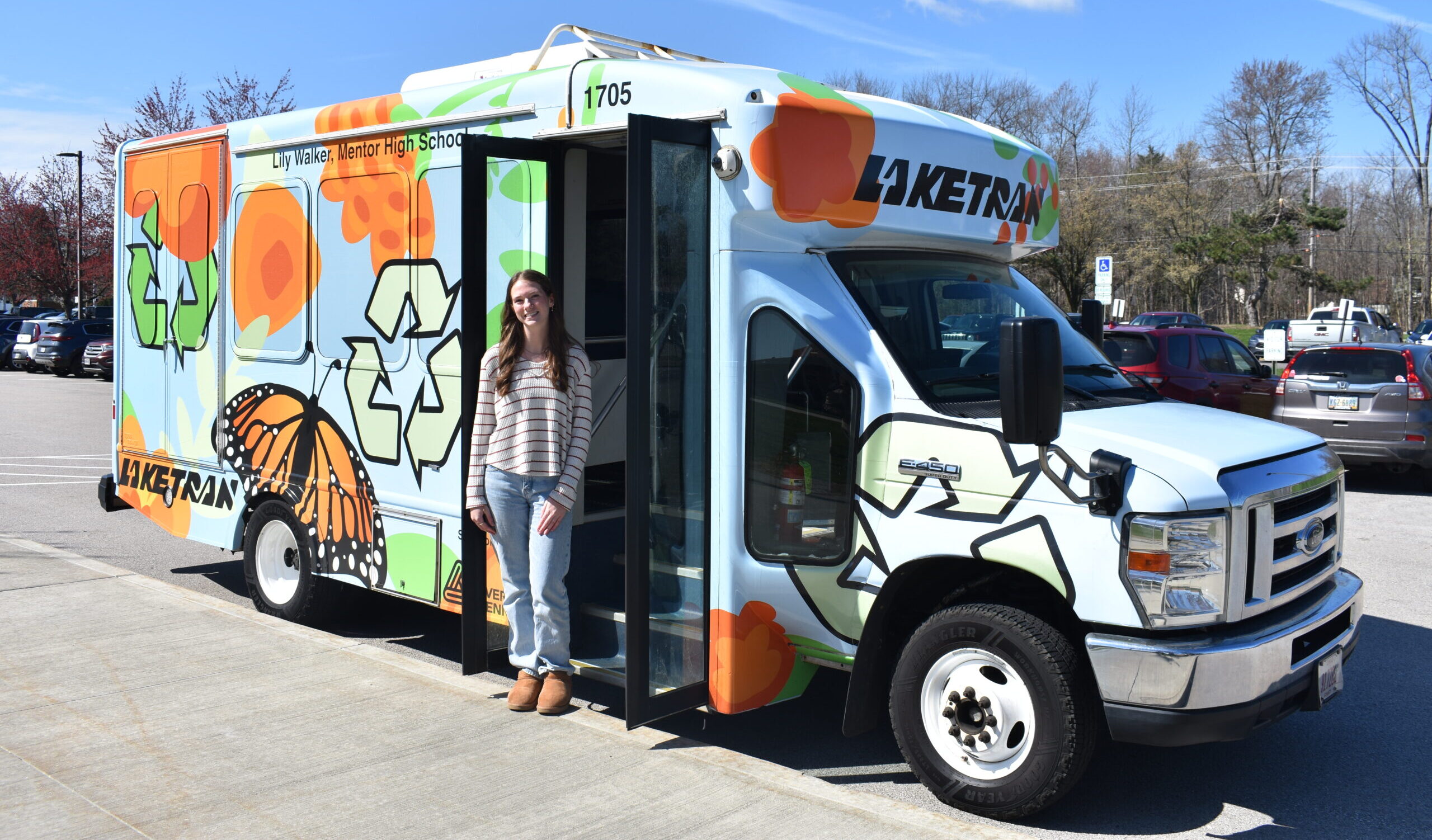 Mentor student Lily Walker poses with her winning bus wrap design.