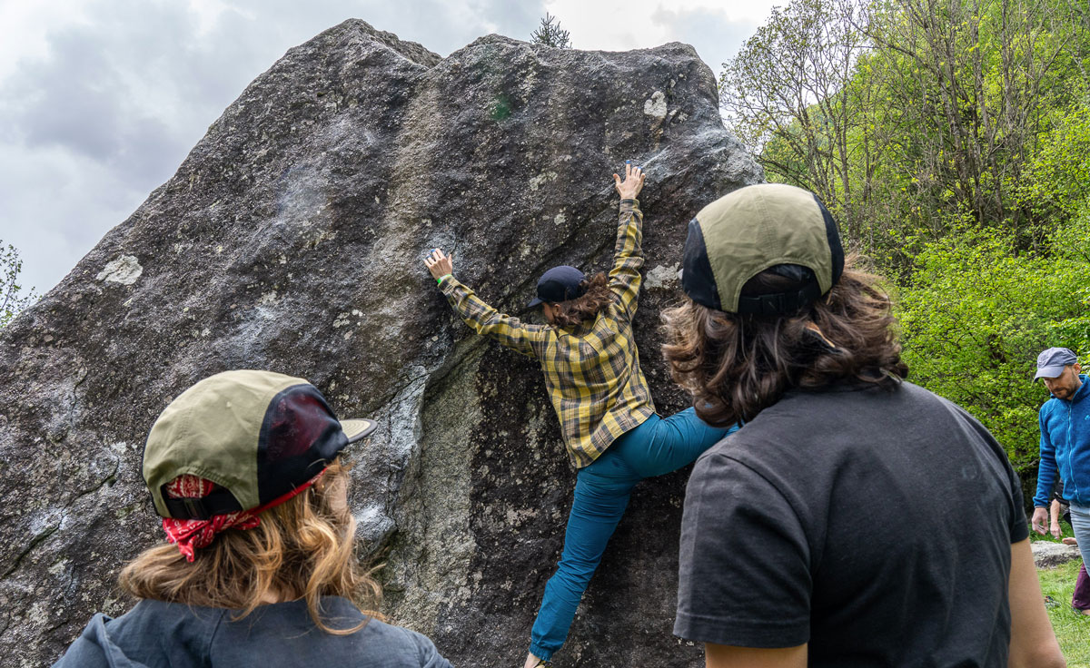 group of people watch as person boudlers on rock face - atlantis