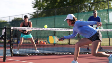 pickleball players sports A woman hits a dink shot while playing pickleball.
