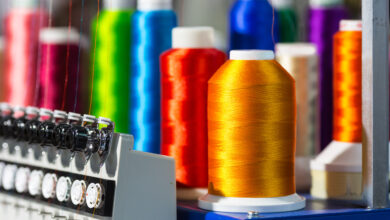 Embroidery machine. Spools of color threads closeup, spinning machine. Cloth factory, weaving, textile production, clothing industry, sewing fabric
