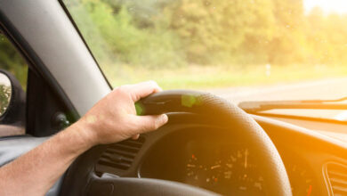 Man is holding hands on the car's steering wheel. Raindrops on the windscreen. Guy is traveling in the bad weather. Dangerous conditions. Lifestyle concept.