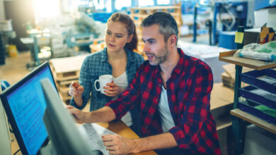 Young man and woman using a computer while working in a printing press office workflow